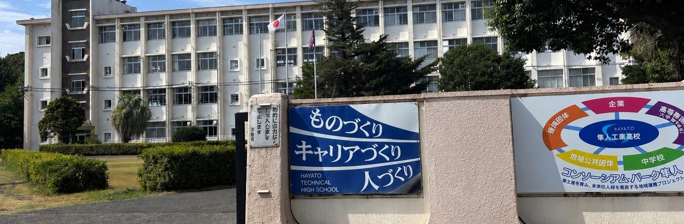 青空の校門から見た校舎。「ものづくり・キャリアづくり・人づくり」の看板